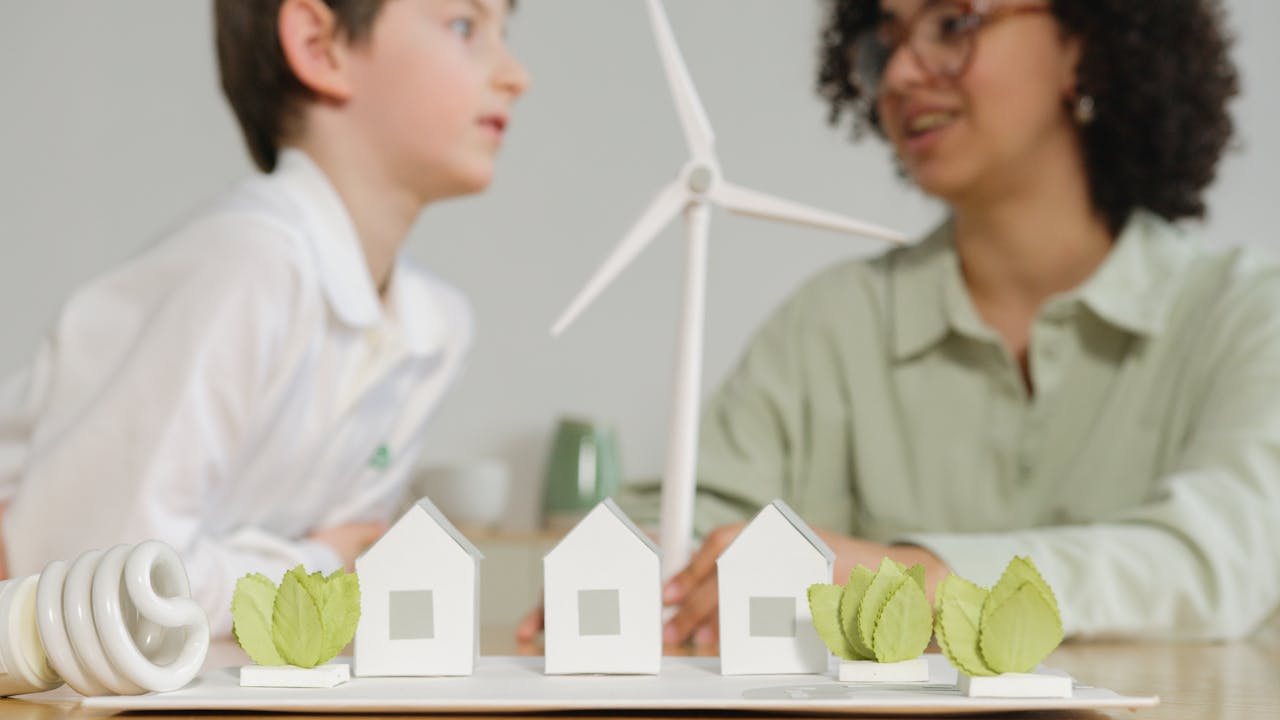 Children engage in learning about renewable energy with wind turbines and eco-friendly models in a classroom setting.